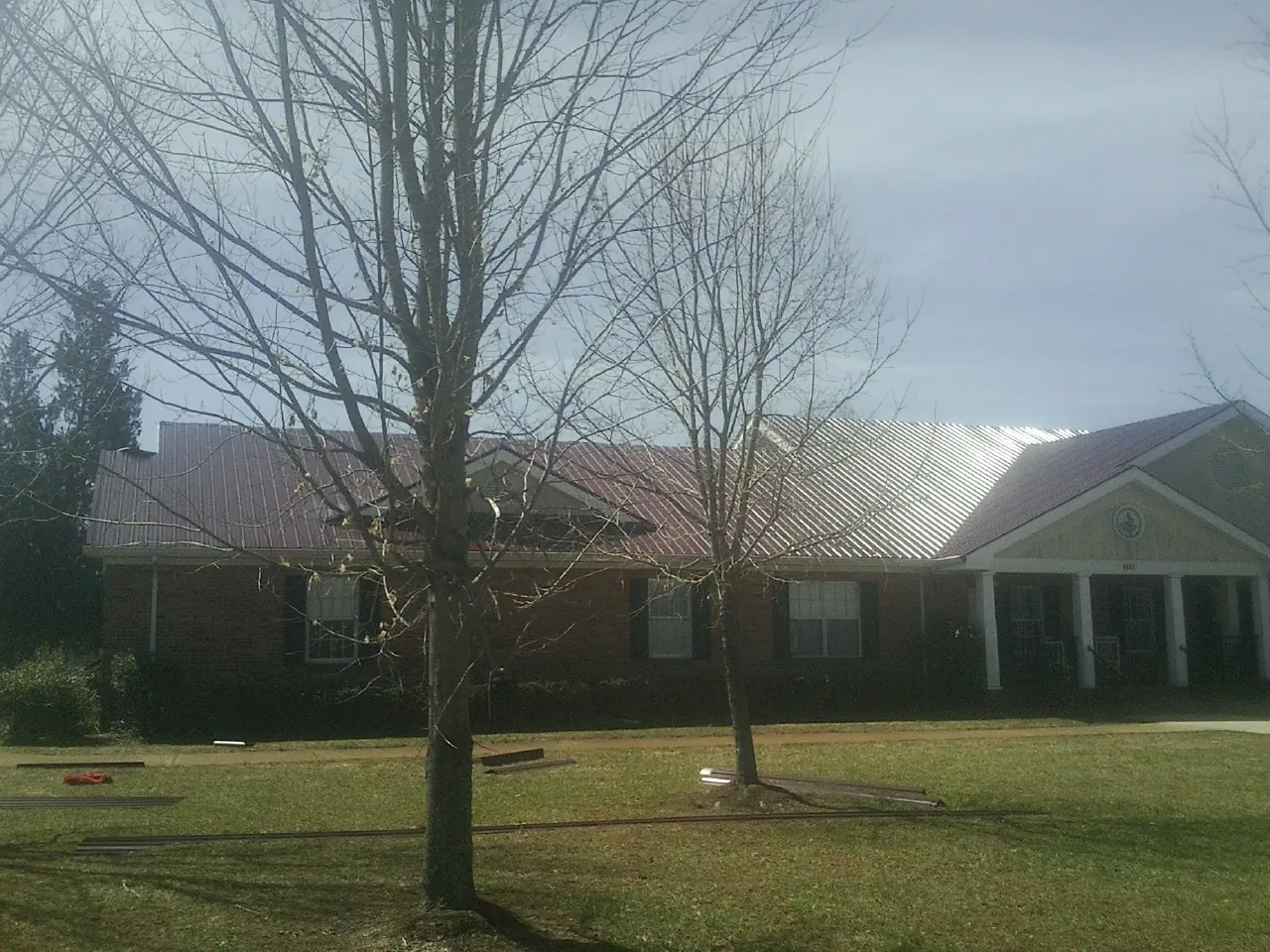 Red metal roof on a brick building seen from the front lawn in Lake Charles