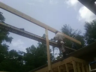 Carpenter setting a ridge beam over a new addition frame — Ice Dam Removal by Roofing Brothers in Lake Charles