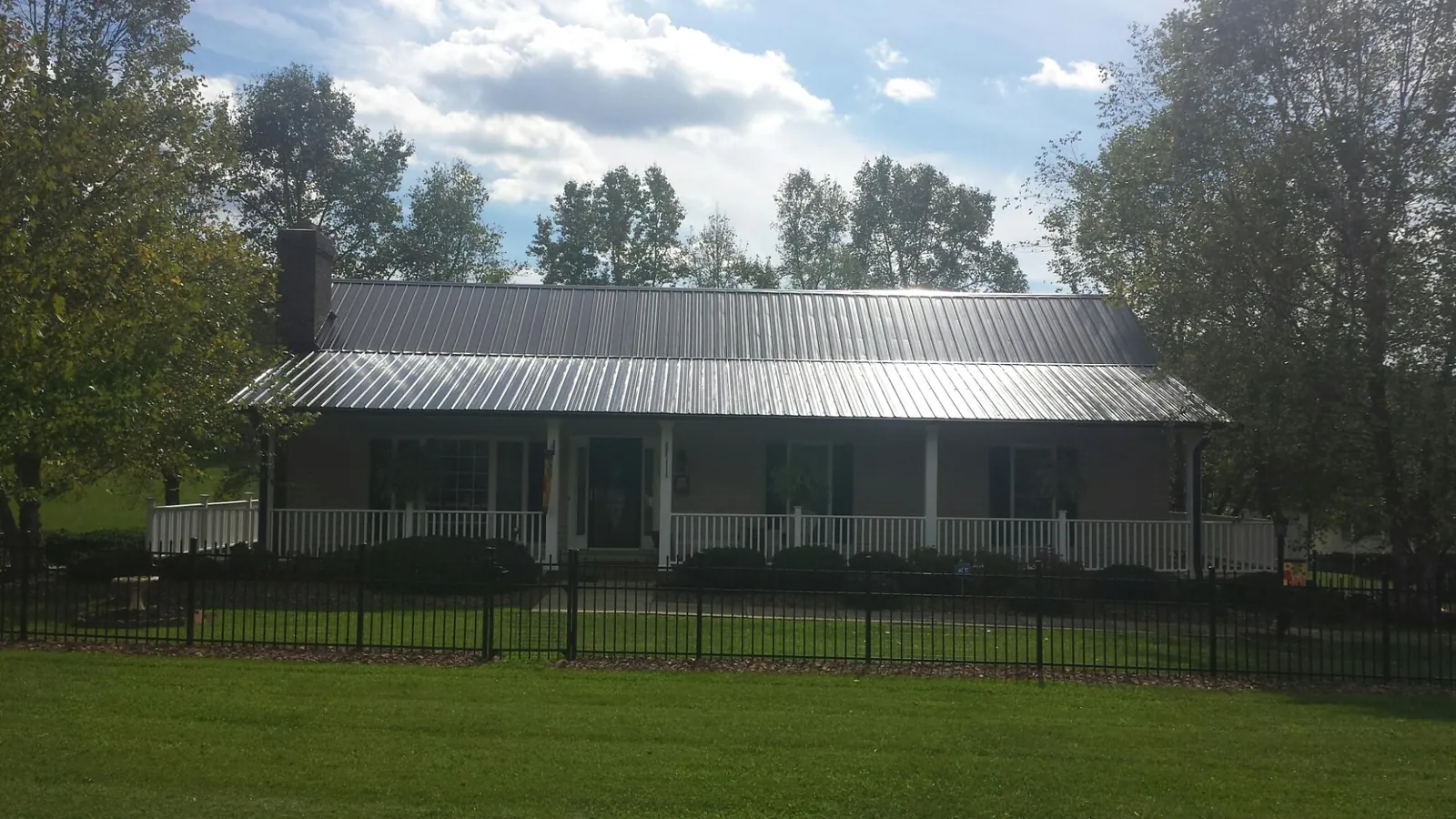 Gray metal roof on a brick ranch with a full width front porch — Gutter Guard Installation work by our crew in Lake Charles