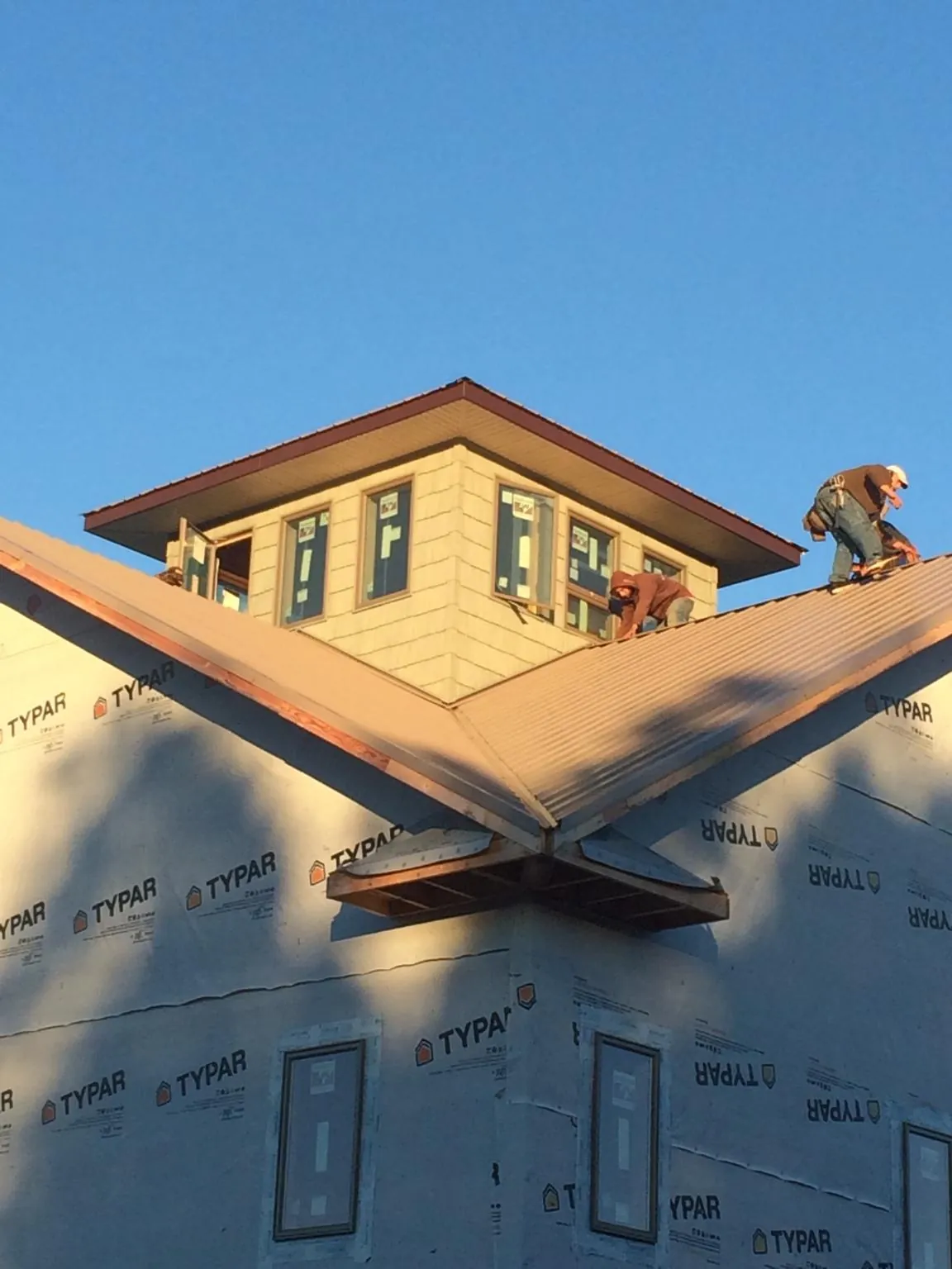 Roofers working around a rooftop cupola on a new metal roof at sunset — Roof Waterproofing in Lake Charles by Roofing Brothers